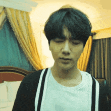 a young man with his eyes closed is standing in a room