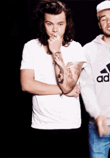 a man with a tattoo on his arm wears a white adidas shirt