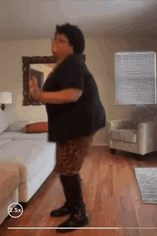 a woman is dancing in a living room with a 2.5x watermark on the bottom of the screen .