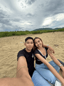 a man and a woman sit on a sandy beach