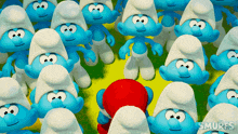 a group of smurfs are gathered together and one of them is standing in the middle