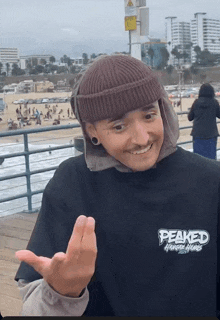a person wearing a peaked shirt and a beanie smiles
