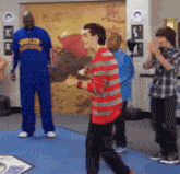 a man in a blue shirt that says ' saddle ' on it stands in a gym