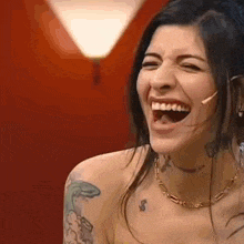 a naked woman is laughing with her mouth open and a tattoo on her arm .