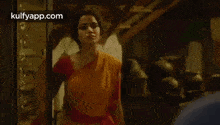 a woman in a yellow saree and red blouse is standing next to a man in a blue shirt .