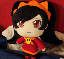 a stuffed doll with red eyes and a yellow skull around her neck