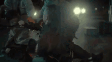a group of people are standing around a man laying on the ground in the dark .
