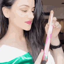 a woman in a green top is holding a pink item in her hand