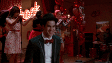 a man in a tuxedo and bow tie is standing next to another man
