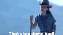 a woman in a cowboy hat is holding a stick and says that 's too damn bad .