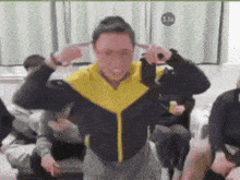 a man in a yellow and black jacket covering his ears