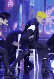 a man in a yellow hat is sitting in a chair on a stage