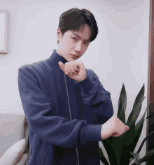 a young man in a blue jacket is making a fist