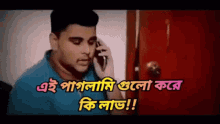 a man in a blue shirt is talking on a cell phone with a red door behind him