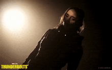 a woman is standing in a dark room with thunderbolts written on the bottom right