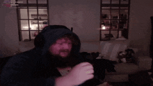 a man with a beard is wearing headphones and a hoodie in a dark room