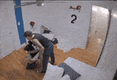 a man is standing in a room with a poster on the wall that has the number 2 on it