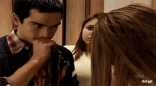a man and a woman are looking at each other . the woman is covering her mouth with her hand .
