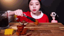 a woman in a red sweater is holding a tong over a piece of food