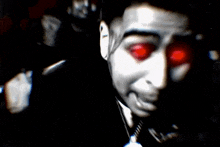 a close up of a man with red eyes in a dark room .