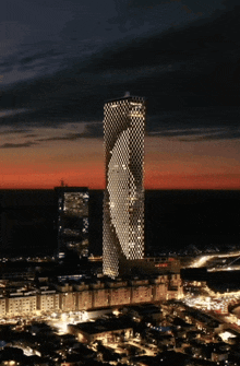 a very tall building is lit up at night and says ' allianz ' on it