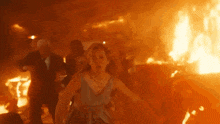 a woman in a blue dress runs through a fire