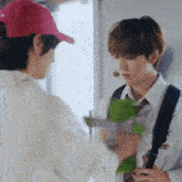 a man wearing a pink hat is talking to another man wearing a white shirt and tie
