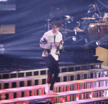 a man is running on a stage with a drummer in the background
