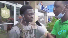 a man wearing a mask is talking into a microphone in front of a domino 's pizza shop .