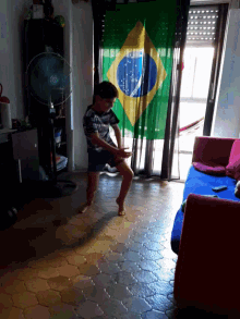a boy is laying on the floor in front of a large brazilian flag