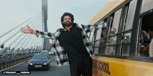 a man standing next to a yellow school bus with his arms outstretched