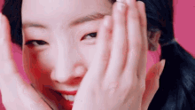 a close up of a woman covering her face with her hands while smiling .