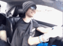 a man wearing a beanie and sunglasses is sitting in the back seat of a car