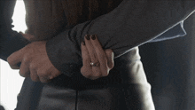 a woman wearing a ring is hugging a man
