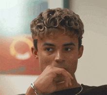 a young man with curly hair looks at the camera
