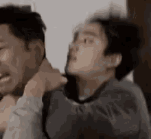 a man is holding another man 's neck while another man looks on .