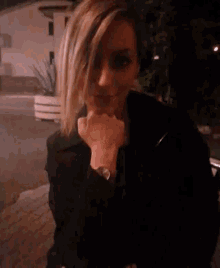 a woman wearing a black jacket and a watch looks at the camera