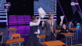 a group of people in school uniforms are on a stage with a mnet logo behind them