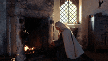 a woman kneeling in front of a fireplace with a tumblr.com watermark on the bottom right