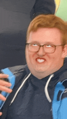 a man with glasses and a blue jacket making a funny face