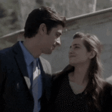 a man in a suit and tie is kissing a woman on the forehead