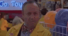 a man in a yellow jacket and bow tie is holding a stuffed animal in his hand .
