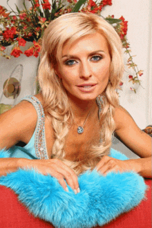 a blonde woman wearing a blue fur collar and a necklace