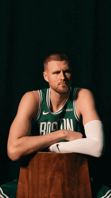 a boston celtics player sits on a wooden box