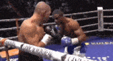 two men are fighting in a boxing ring and one of them is wearing everlast gloves .