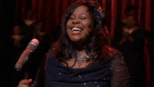 a woman singing into a microphone with a feather in her hair