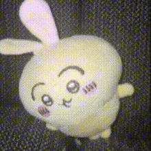 a stuffed bunny with a pink ear is sitting on a black background
