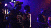 a group of men are dancing on a stage and one of them is wearing a shirt that says b on it