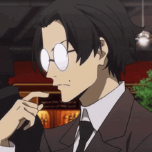 a man in a suit and tie with glasses holds his hand to his nose