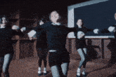 a group of women are dancing in front of a blackboard in a dark room